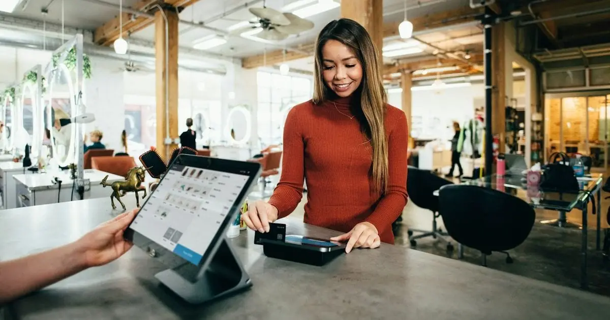 A retail worker taking a card payment at a shop counter