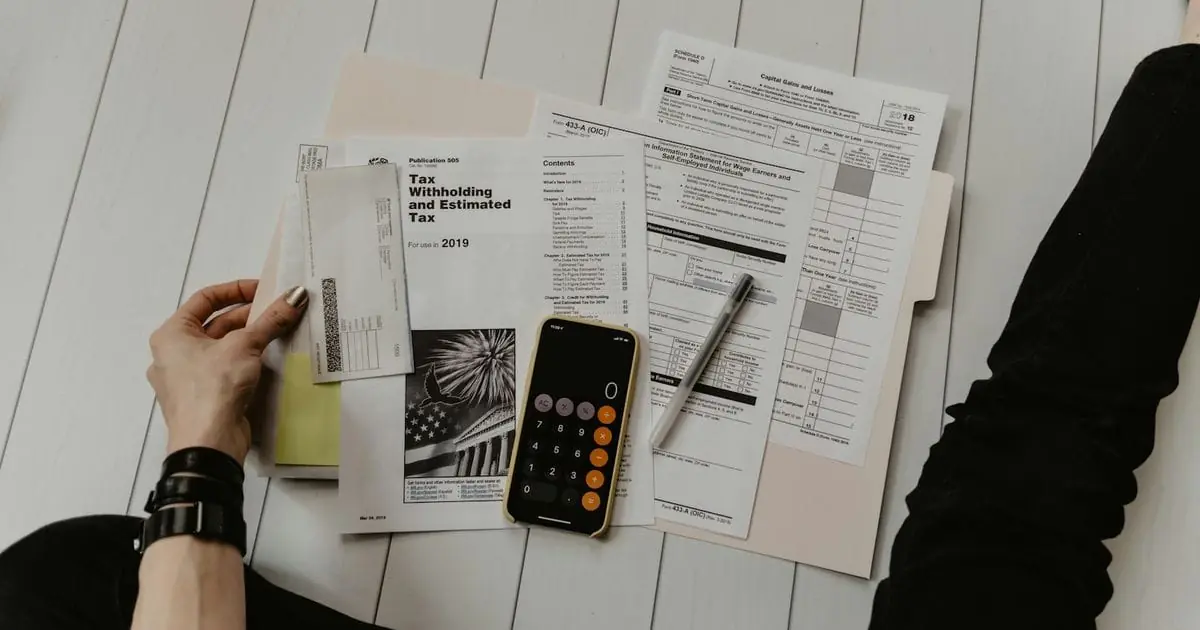 A person working through tax paperwork with a calculator and pen
